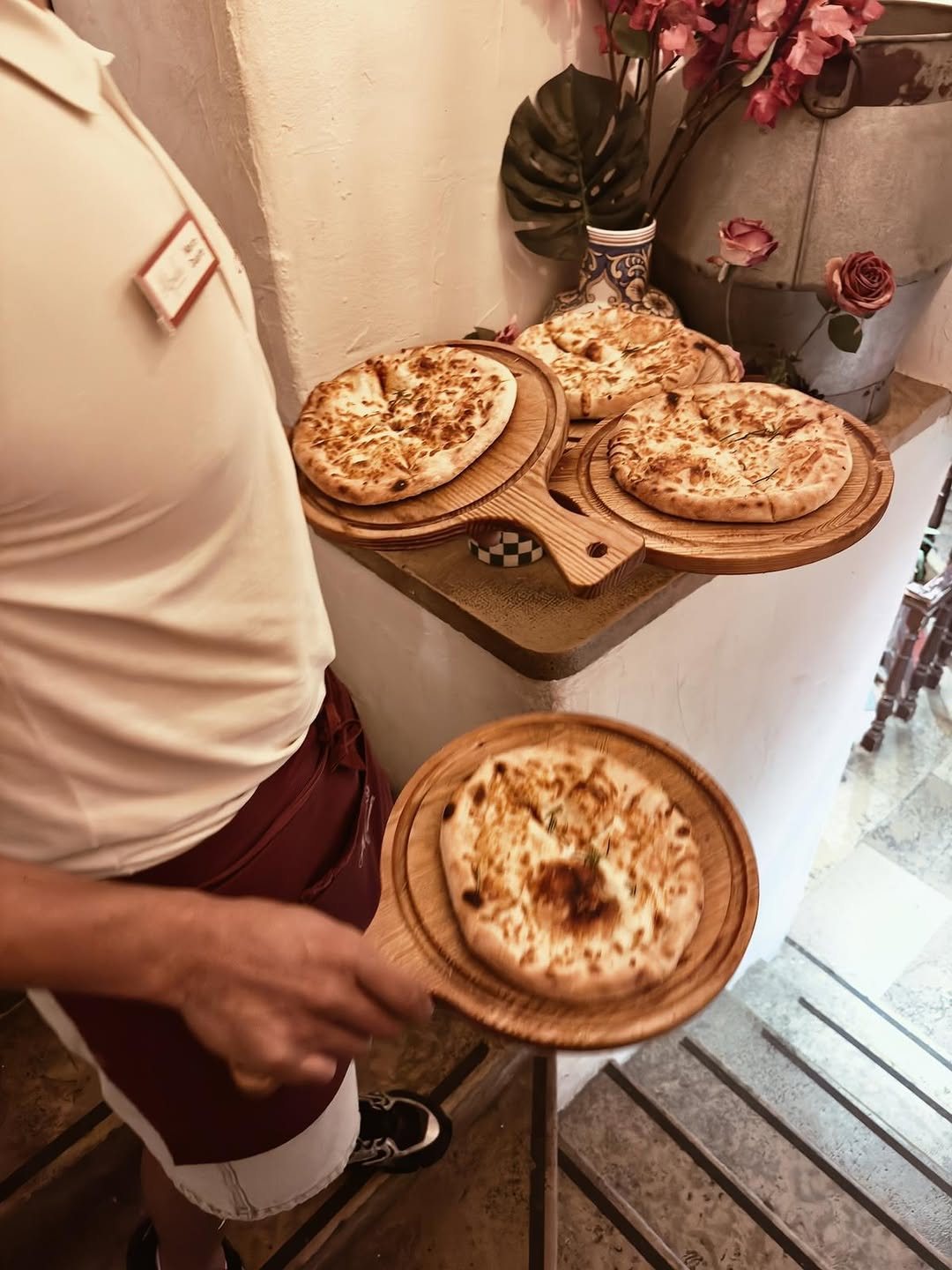 Empregado a levar pão de alho com queijo em tábuas redondas de madeira por umas escadas